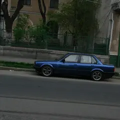 Blue BMW E30 sedan, lowered side profile on the street