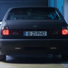 Matte-black BMW 7-series rear view with red tail lights on, Bucharest license plate