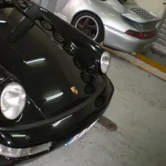 Two air-cooled Porsche 911s — a black 964 and a silver 993 — side by side in a workshop